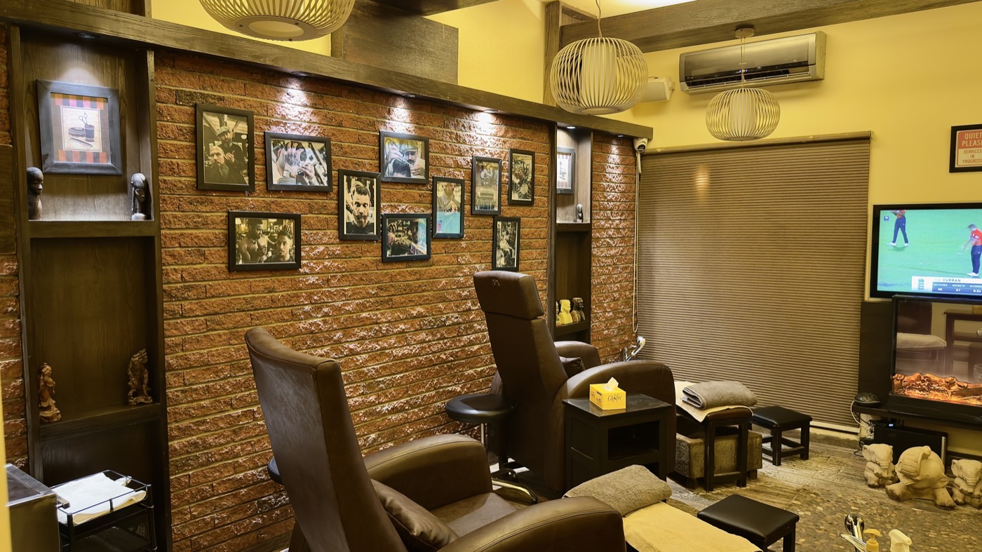 Barber chairs against an exposed brick wall hung with framed pictures at the Stadium branch